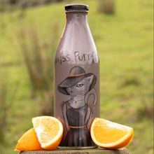 Load image into Gallery viewer, Bottle with a cat illustration labeled &#39;Miss Purrfect&#39; next to orange slices on a wooden surface with a grassy background